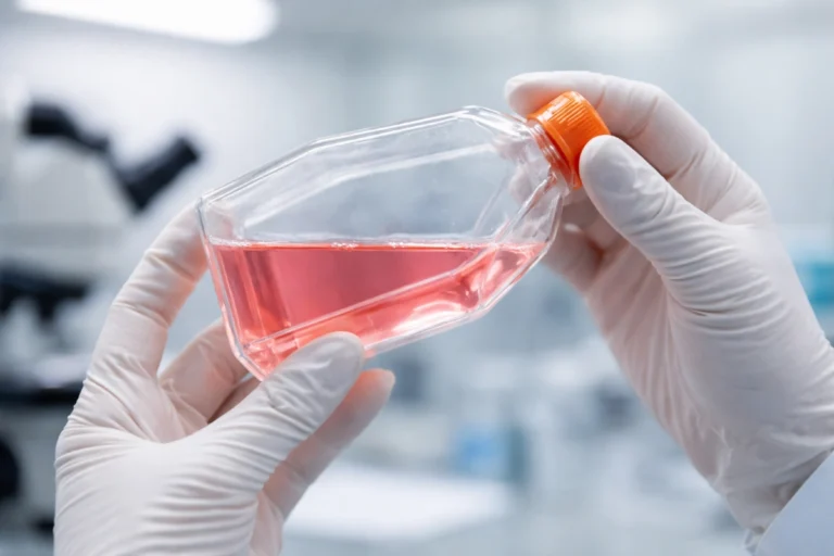 Researcher holding cell culture flask in lab